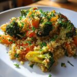 A serving of Herbed Quinoa with Roasted Vegetables, featuring bright green broccoli florets and orange carrots, garnished with fresh parsley.