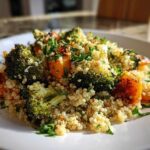 A close-up serving of Herbed Quinoa with Roasted Vegetables, featuring roasted broccoli and sweet potato chunks.