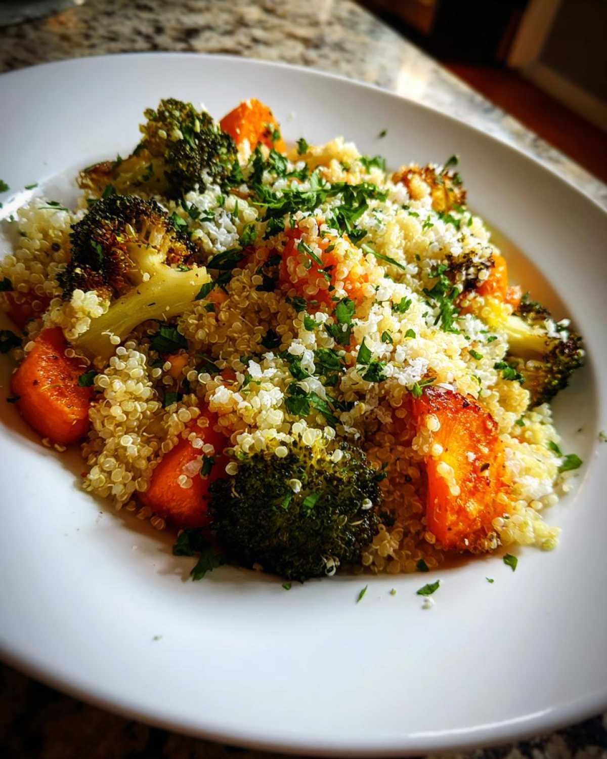 A close-up of Herbed Quinoa with Roasted Vegetables, featuring roasted broccoli and carrots mixed with fluffy quinoa and fresh parsley.