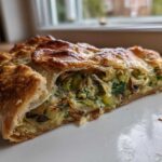A close-up cross-section of a golden, flaky Leek Mushroom Galette slice showing the savory filling.