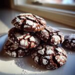 A close-up stack of rich, dark Mexican Chocolate Crinkle Cookies heavily dusted with white powdered sugar.