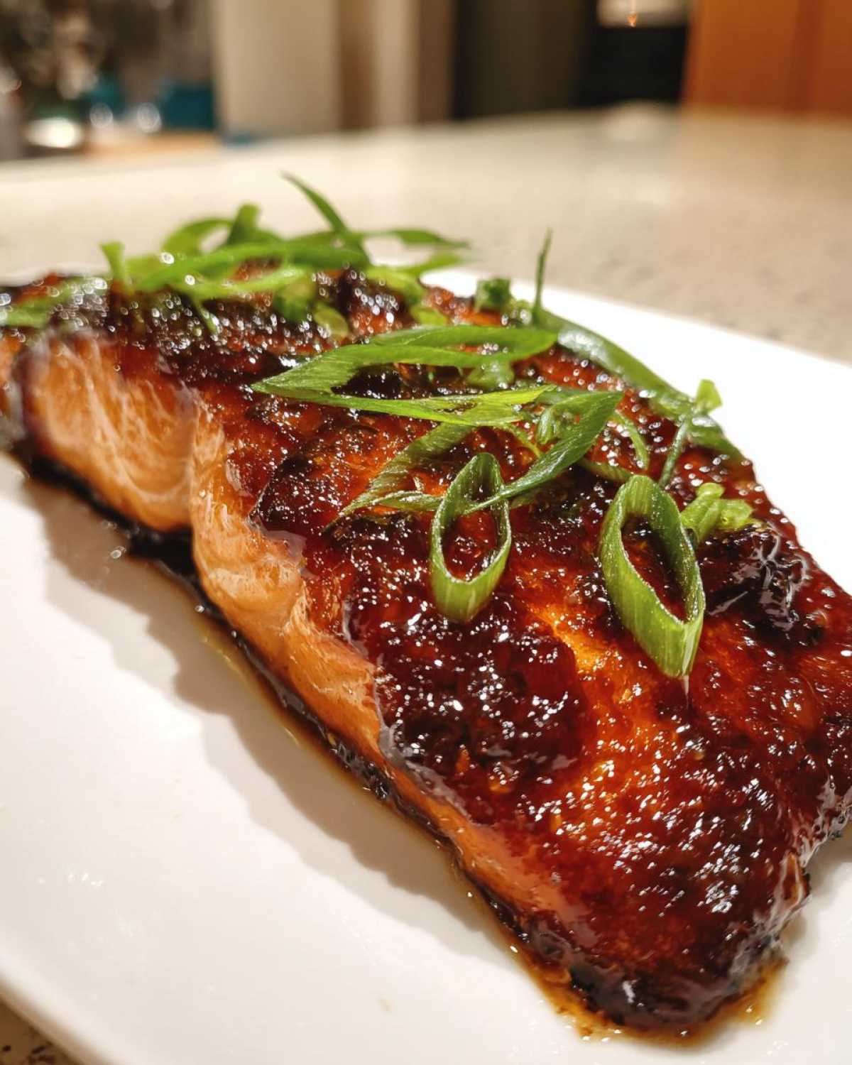 A close-up of a perfectly cooked Miso Glazed Salmon with Scallions, featuring a dark, caramelized glaze.