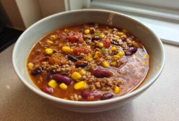 Close-up of a hearty bowl of One-Pot Taco Soup with Lime, featuring ground meat, kidney beans, and corn in a rich broth.