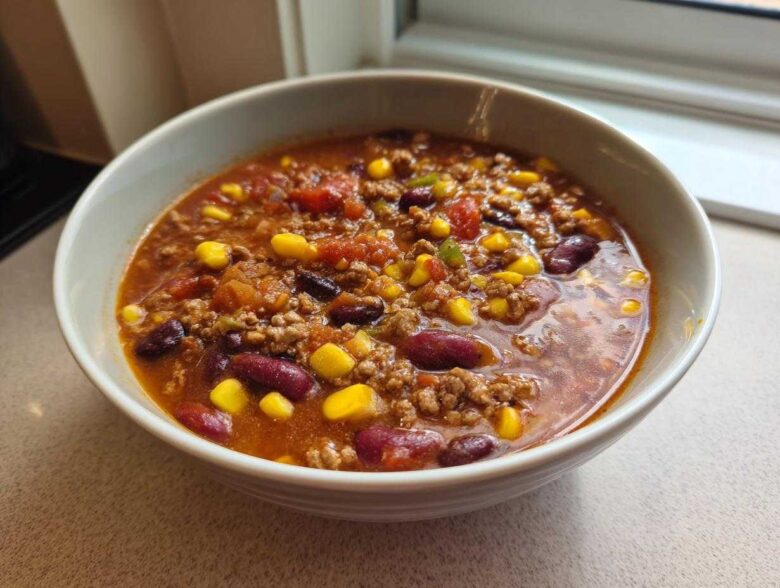 Close-up of a hearty bowl of One-Pot Taco Soup with Lime, featuring ground meat, kidney beans, and corn in a rich broth.
