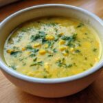 Close-up of a bowl of creamy yellow Poblano Corn Chowder with whole corn kernels and fresh cilantro topping.
