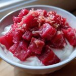 Close-up of bright pink Rhubarb Ginger Compote for Yogurt served in a white bowl.
