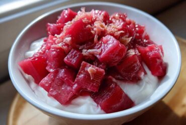 Close-up of bright pink Rhubarb Ginger Compote for Yogurt served in a white bowl.