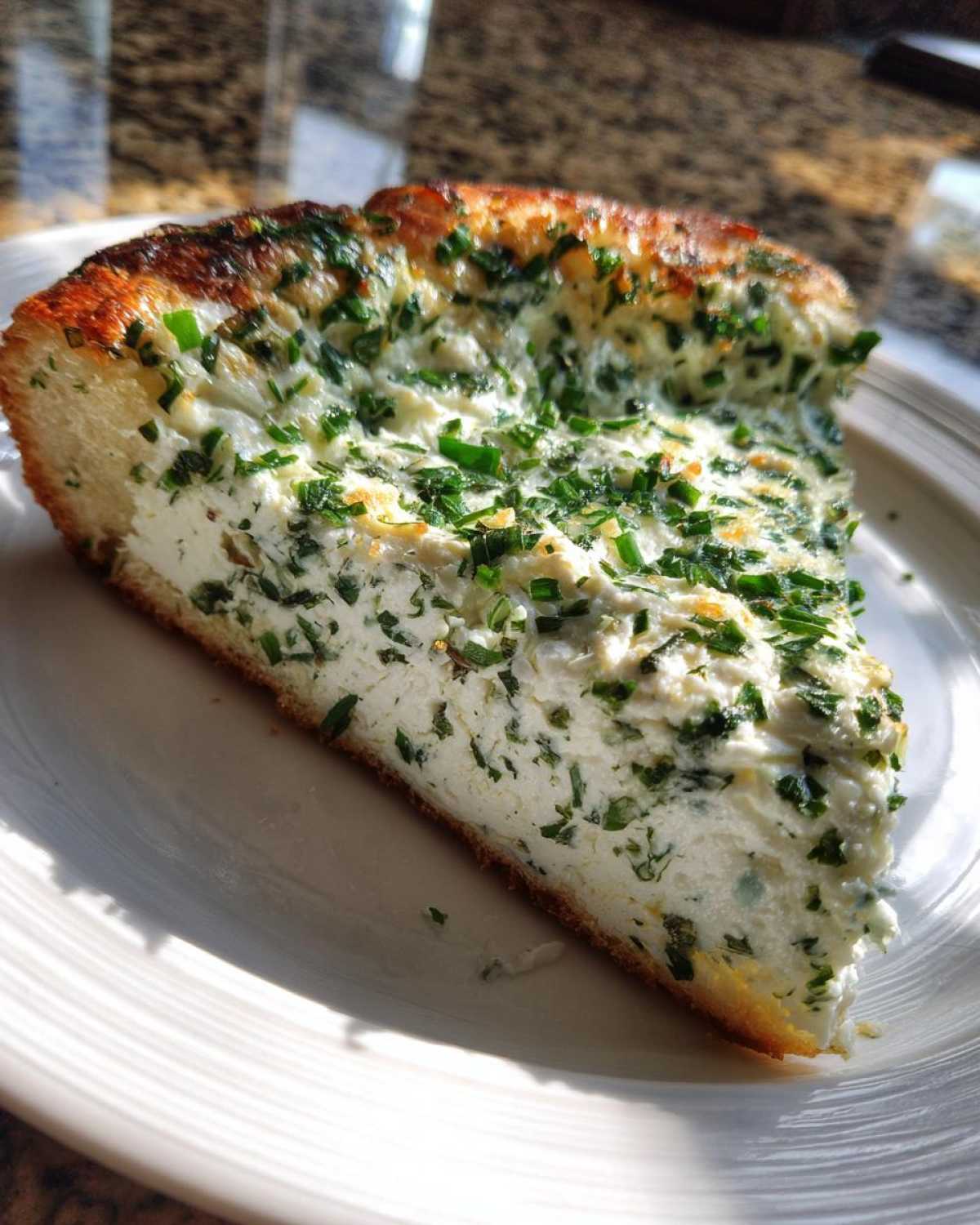 A thick slice of Ricotta Herb Brunch Pizza, showing a creamy white ricotta filling topped generously with fresh green herbs.