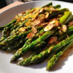 Bright green Roasted Asparagus with Almond Crunch, topped with sliced almonds and lemon zest.