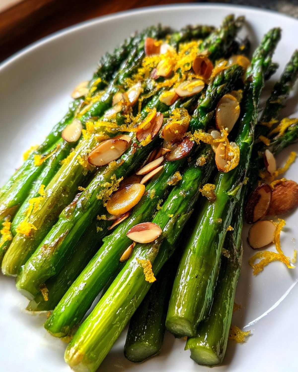 Bright green roasted asparagus spears topped with sliced almonds and lemon zest for Roasted Asparagus with Almond Crunch.