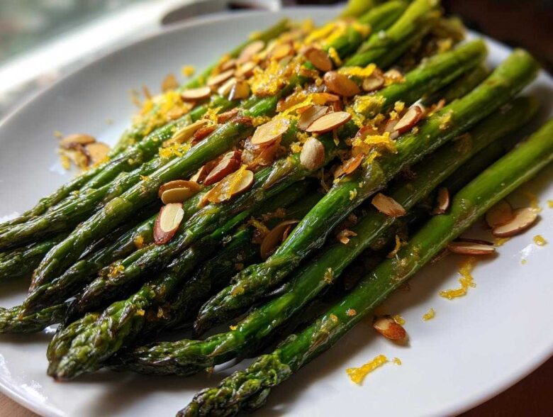 Close-up of bright green Roasted Asparagus with Almond Crunch, topped with slivered almonds and orange zest.