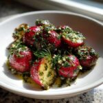 Close-up of roasted radishes with garlic and dill, glistening in oil, served in a white bowl.