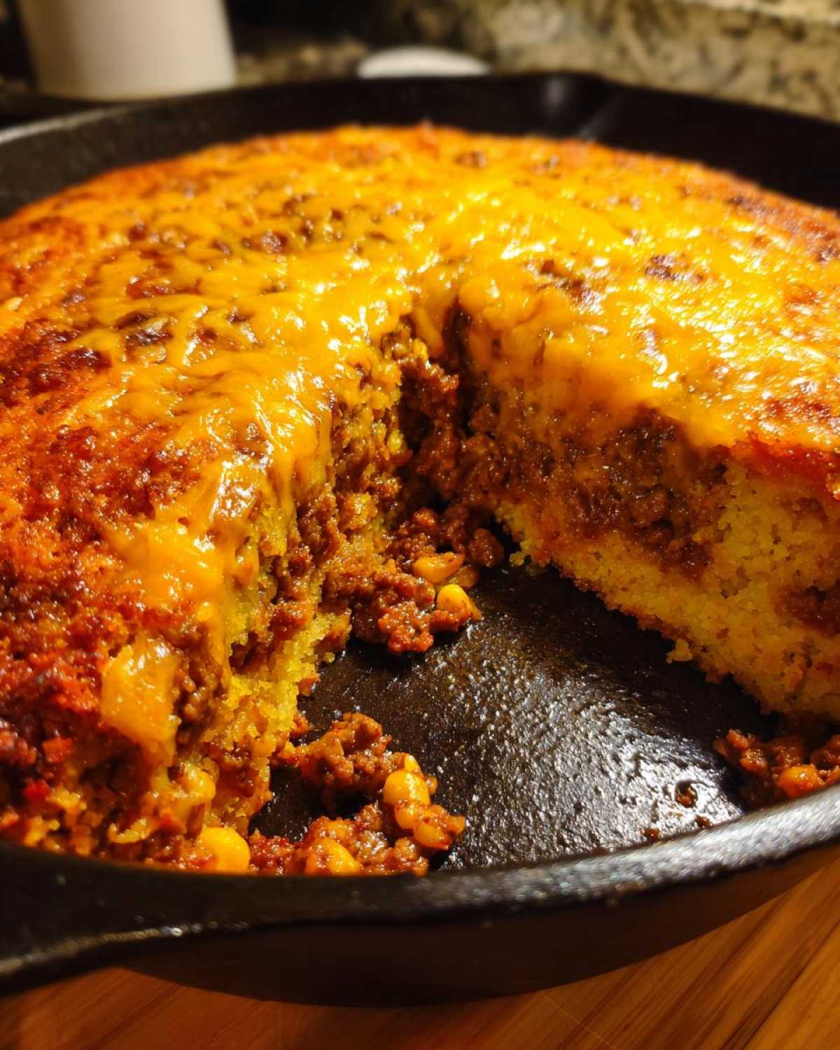 A slice has been removed from the Skillet Tamale Pie with Cornbread Top, showing the cheesy, meaty filling and golden cornbread crust.
