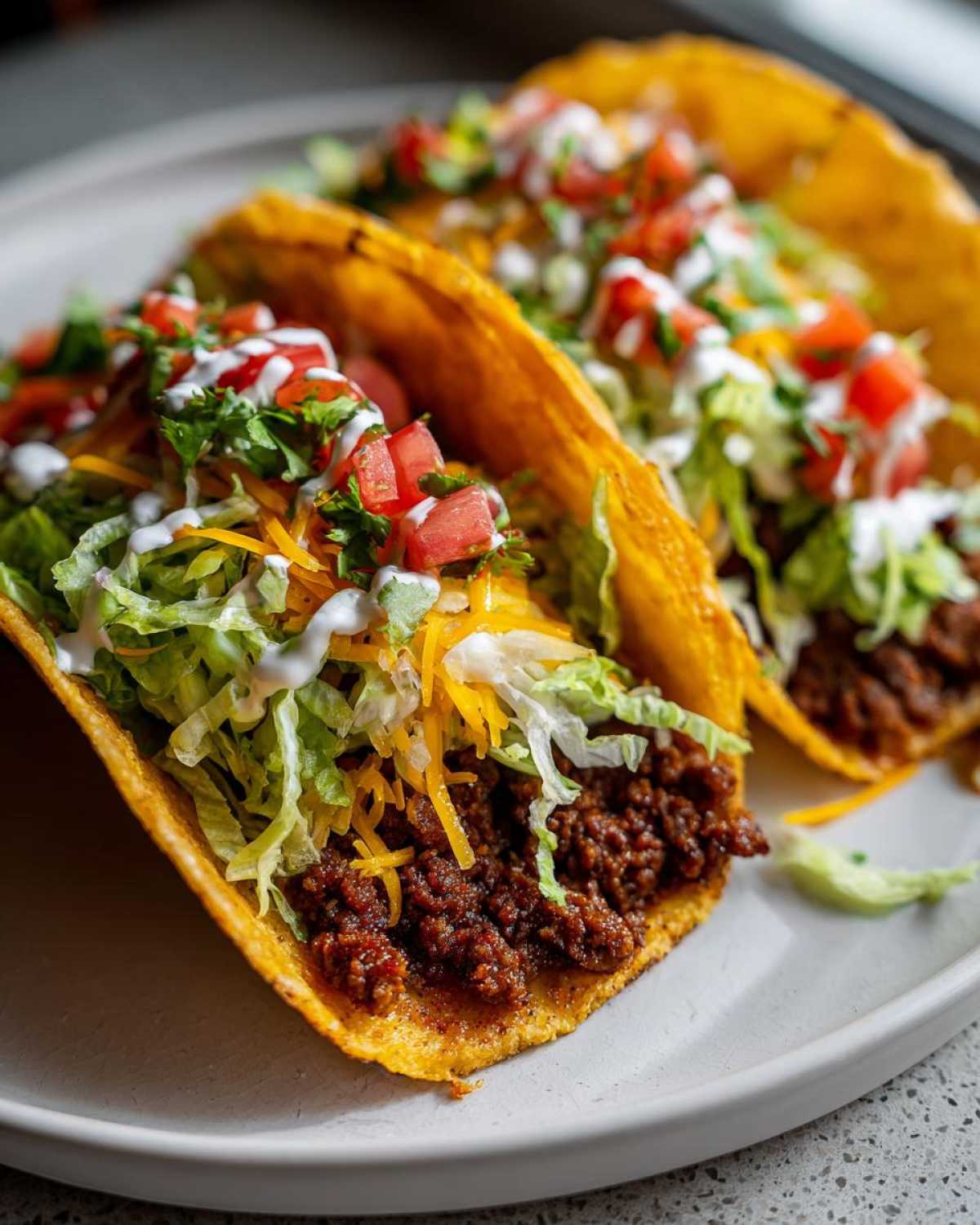 Two crispy tacos filled with seasoned ground beef, shredded lettuce, cheese, diced tomatoes, and sour cream, representing Smash Burger Tacos.