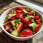 Close-up of vibrant Strawberry Avocado Salsa with Lime, featuring chunks of red strawberries and green avocado in a white bowl.