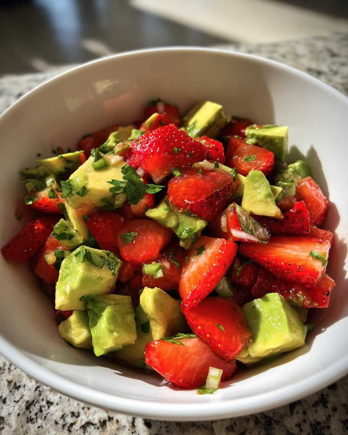 Close-up of vibrant Strawberry Avocado Salsa with Lime, featuring diced strawberries and avocado chunks in a white bowl.