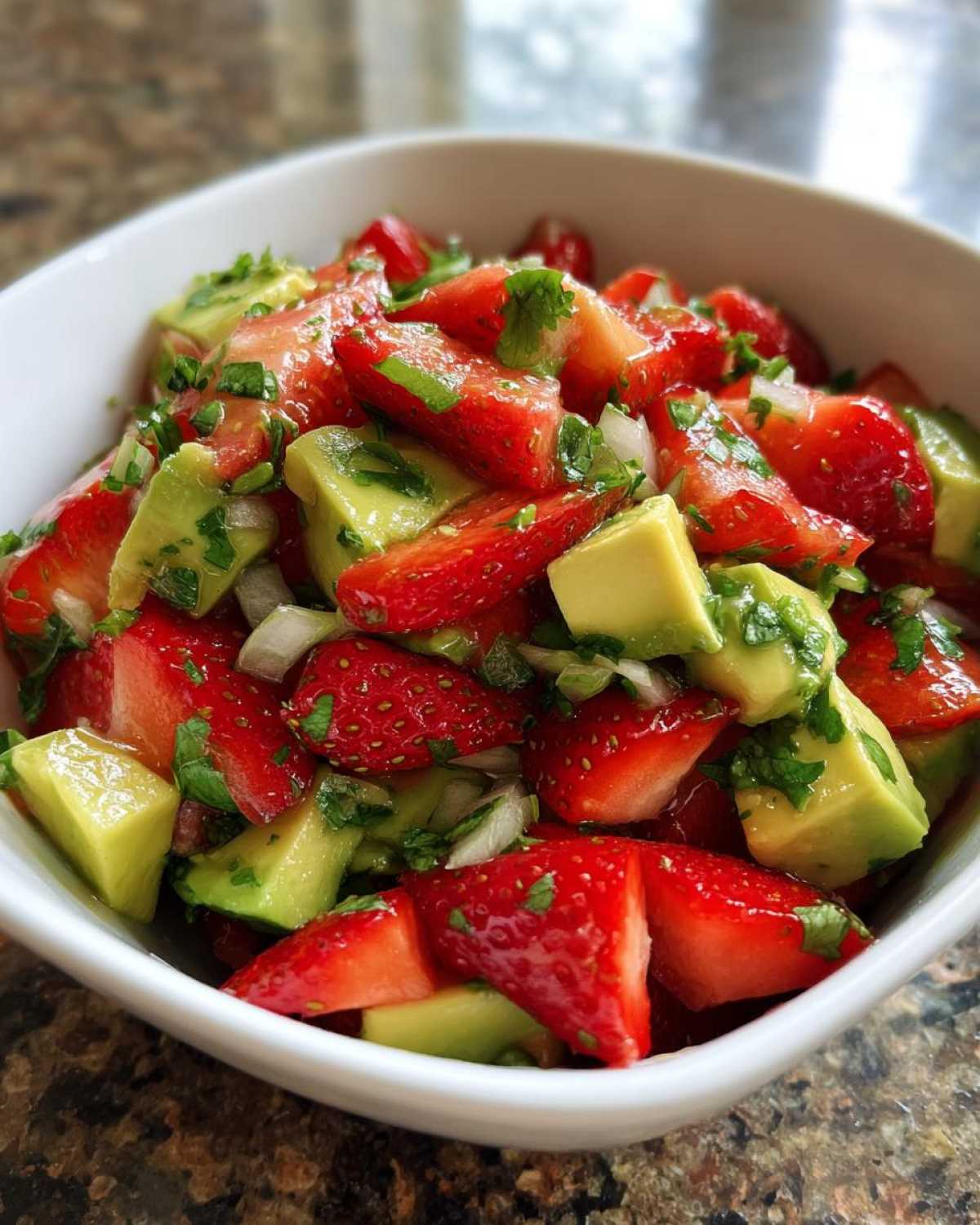 Close-up of vibrant Strawberry Avocado Salsa with Lime, featuring chunks of red strawberries and green avocado in a white bowl.