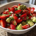 Close-up of vibrant Strawberry Avocado Salsa with Lime, featuring chopped strawberries, avocado chunks, and onions in a white bowl.