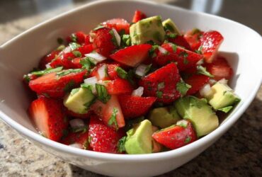 Close-up of vibrant Strawberry Avocado Salsa with Lime, featuring chopped strawberries, avocado chunks, and onions in a white bowl.