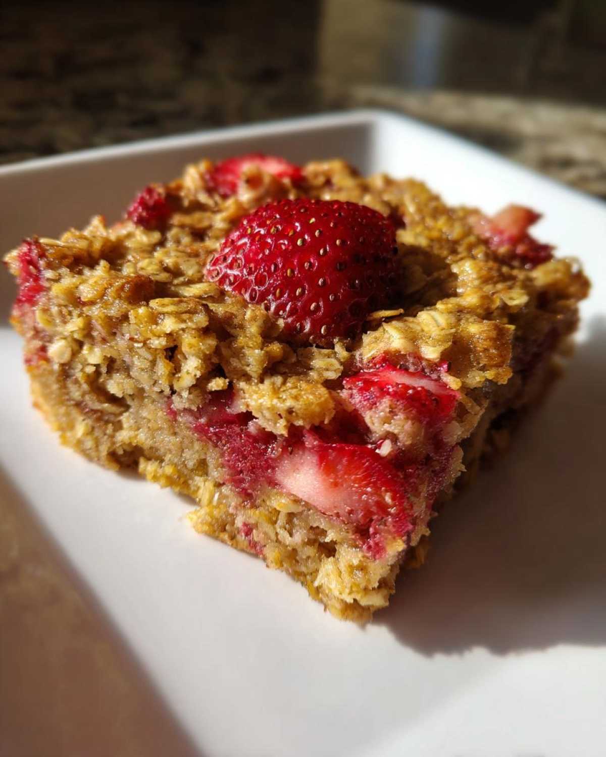 Close-up of a single serving of Strawberry Baked Oatmeal Breakfast Squares topped with a whole strawberry.