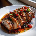 Close-up of sliced Strawberry Balsamic Pork Tenderloin covered in a rich, glossy strawberry and herb glaze.