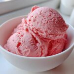Three scoops of bright pink Strawberry Banana Nice Cream served in a small white bowl.