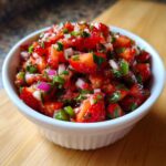 Close-up of fresh Strawberry Jalapeno Salsa with diced strawberries, red onion, and cilantro in a white bowl.
