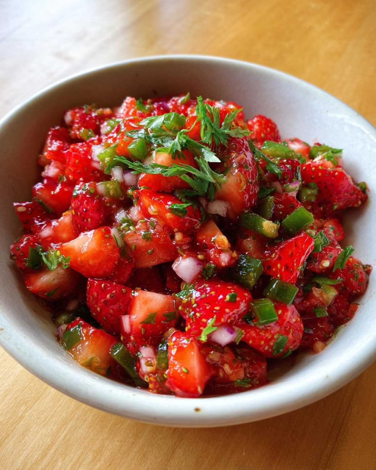 Close-up of vibrant Strawberry Jalapeno Salsa featuring diced strawberries, green jalapeño, and cilantro in a light bowl.