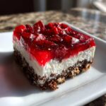 A close-up of one square of Strawberry Pretzel Salad Dessert Squares showing the pretzel crust, cream cheese layer, and bright red strawberry topping.