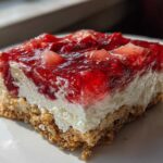 A single square of Strawberry Pretzel Salad Dessert Squares showing the pretzel crust, cream cheese layer, and bright red strawberry topping.