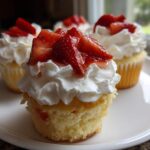 Close-up of a delicious Strawberry Shortcake Cupcakes with Whipped Cream, topped with macerated strawberries.