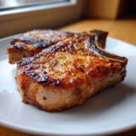 Close-up of two beautifully caramelized Vietnamese Lemongrass Pork Chops on a white plate.